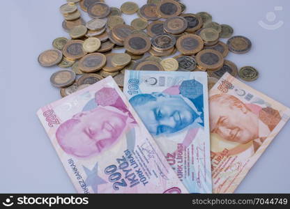 Turkish Lira coins and banknotes side by side on white background