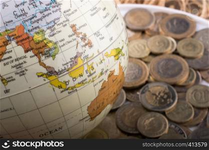 Turkish Lira coins by the side of a model globe on white background