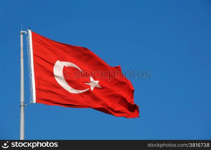 Turkish national flag waves in the breeze against the blue sky background