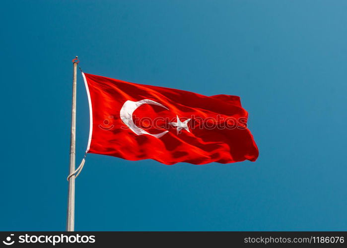 Turkish national flag with white star and moon on a pole in sky