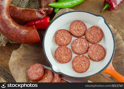 Turkish sausage sucuk slices on a frying pan for breakfast,top view.