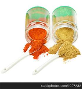 Turmeric and chili pepper powder in glass jar. Heap. Spoon. Isolated on white.