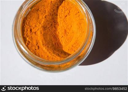 Turmeric powder spice on glass jar isolated on white background 