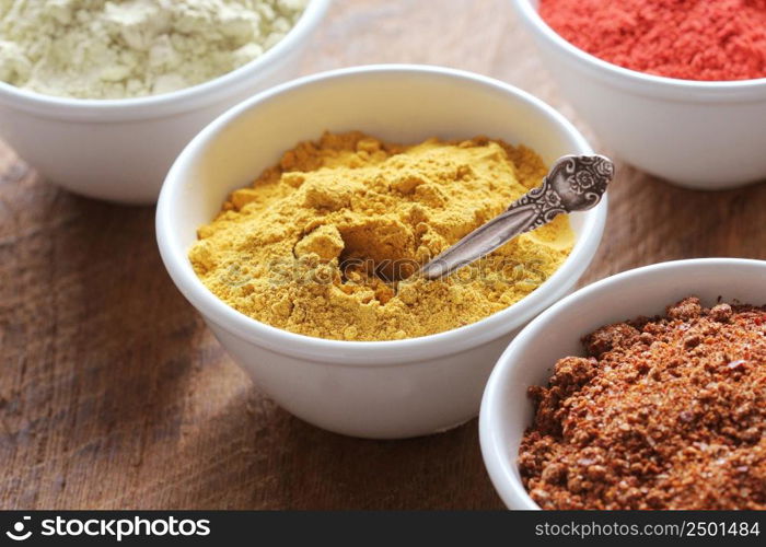 Turmeric powder. Various colorful spices on wooden table in bowls . Food and cuisine ingredients .. Turmeric powder.Various colorful spices on wooden table in bowls . Food and cuisine ingredients.