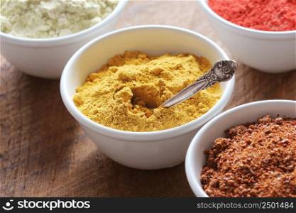 Turmeric powder. Various colorful spices on wooden table in bowls . Food and cuisine ingredients .. Turmeric powder.Various colorful spices on wooden table in bowls . Food and cuisine ingredients.