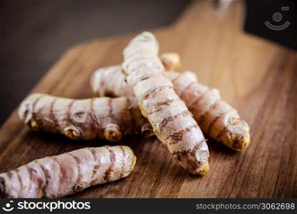 Turmeric root on a wooden cutting board. Turmeric root on a cutting board
