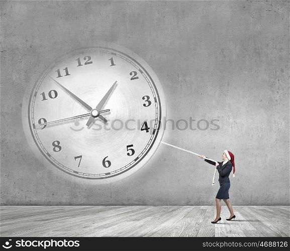 Turn back the time. Woman in Santa hat pulling clock with rope