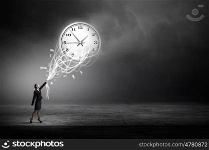 Turn back time. Rear view of businesswoman moving arrow on clock