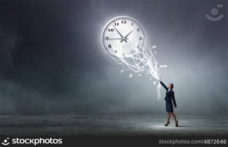 Turn back time. Rear view of businesswoman moving arrow on clock