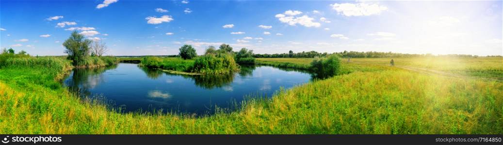 Turn of the river in the middle of meadow with green grass. Panorama. Summer landscape. Turn of river in middle of meadow with green grass