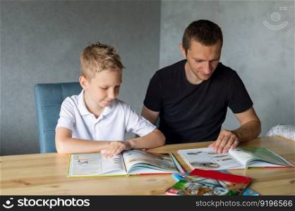 turn the page, look at pictures, read a book, drawings, flip through a page, home leisure, child and parent. boy, dad and son, home schooling, sitting at the table, lots of books. A cute boy is sitting at the table with his dad and watching a book about snakes
