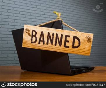 turned off laptop with a wooden sign that says banned. notebook banned text