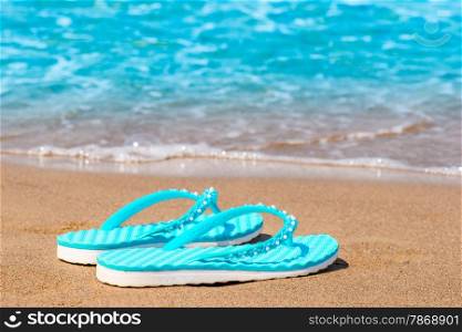 Turquoise flip flops abandoned on a sandy seashore