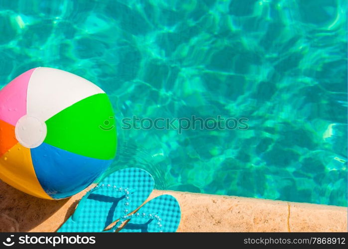 turquoise flip flops and ball on the edge of the pool