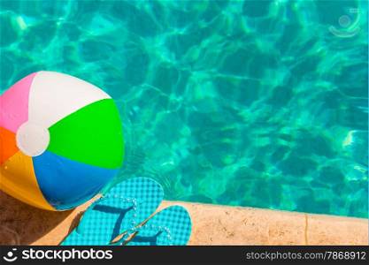 turquoise flip flops and ball on the edge of the pool