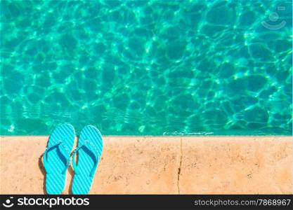 turquoise flip flops at the edge of the pool