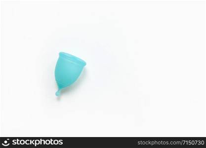 Turquoise menstrual cup on white background. Concept zero waste, savings, minimalism, environmental conservation, sustainable lifestyle. Feminine hygiene product, flatlay, copy space. Horizontal.