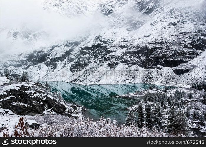 Turquoise mountain lake. Winter and snow in mountain valley.