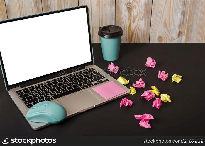 turquoise mouse adhesive note takeaway cup crumpled paper laptop showing white screen display black background