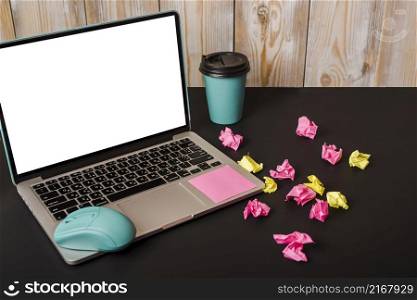 turquoise mouse adhesive note takeaway cup crumpled paper laptop showing white screen display black background