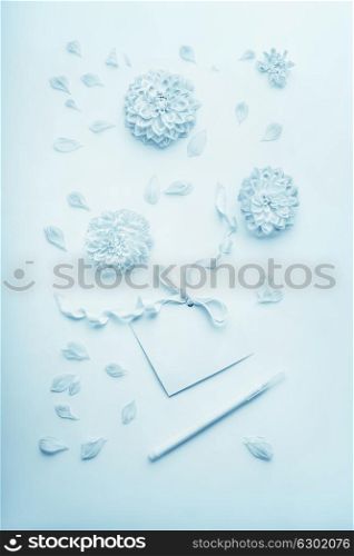 Turquoise pastel blue composition with flowers, blank paper card with ribbon and pencil , flat lay, top view. Layout for greeting of Mothers day, birthday, Valentine?s Day, wedding or happy event