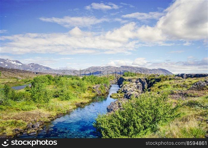 Turquoise river stream in wild icelandic nature with mountains in the background