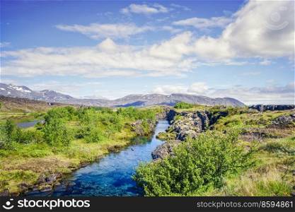 Turquoise river stream in wild icelandic nature with mountains in the background