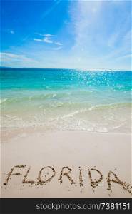 "Turquoise water and golden sand with " florida " written on it. Florida word on a beach"