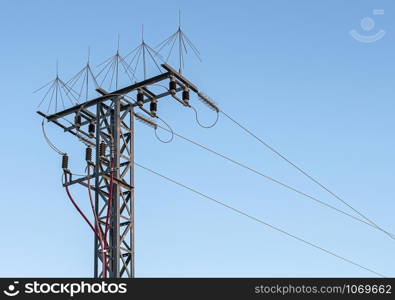 Turret with three power lines and protective elements. Turret with high voltage electricity cables on a fountain of blue sky without clouds