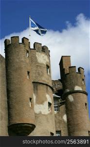 Turrets of a castle in Scotland with Scottish flag blowing in the wind.