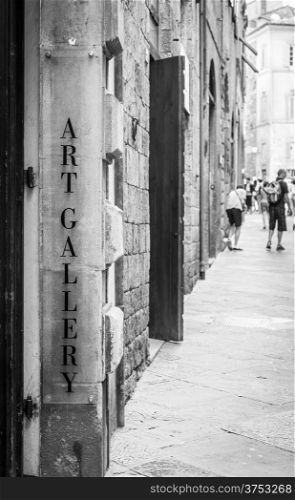 Tuscany, Italy. An art gallery signseen in a street full of turism.