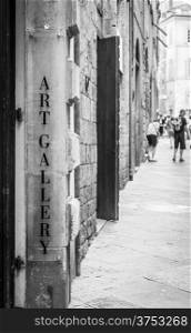 Tuscany, Italy. An art gallery signseen in a street full of turism.