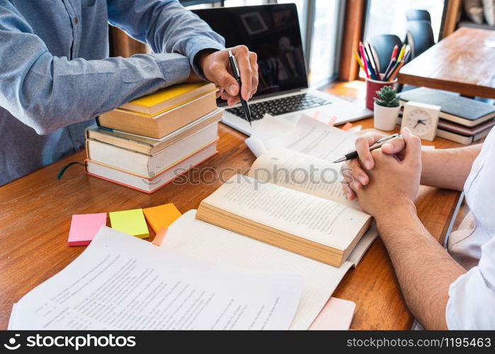 tutor and college students teaching school work and explaining problem solution studying and reading together in a table at class room