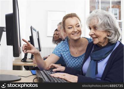Tutor Helping Senior Woman In Computer Class