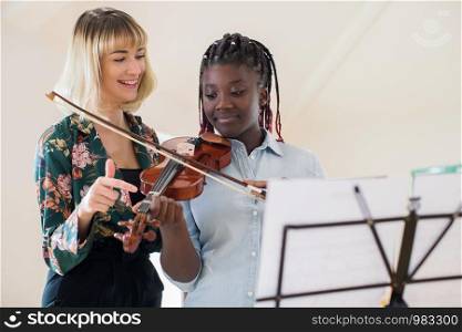 Tutor Teaching High School Student To Play Violin In Music Lesson
