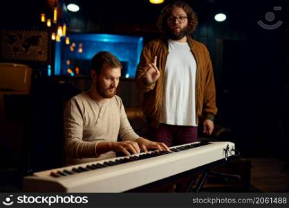 Tutor teaching young guy playing piano synthesizer. Teacher listen and correct student. Music lesson. Tutor teaching young guy playing piano synthesizer