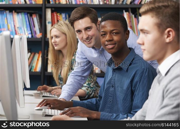 Tutor With Group Of Teenage Students Using Computers