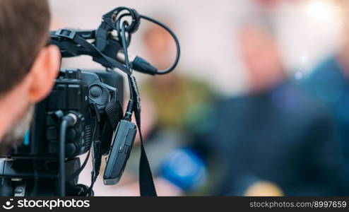 TV camera at a press conference, capturing a video of an unrecognizable speaker which are then broadcasted on television or streamed online. . TV Camera at a Press Conference