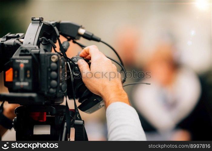 TV camera at a press conference, capturing a video of an unrecognizable speaker which are then broadcasted on television or streamed online. . TV Camera at a Press Conference