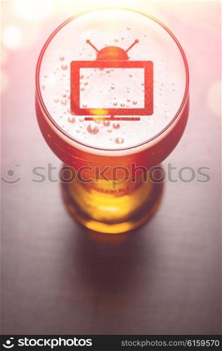 tv set symbol on foam in glass on black table, view from above