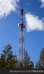 TV Transmission tower in forest against the background of blue sky