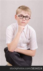 Twelve year old boy with glasses sitting on a chair