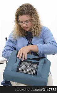 Twelver year old girl with curly blonde hair and glasses putting papers into binder.