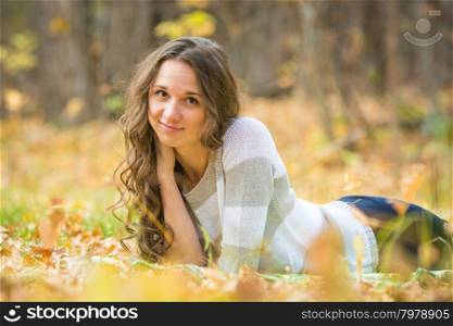 Twenty-five young beautiful girl walks by Europeans autumn forest. Young beautiful girl lies on the Scourge in the yellow fallen leaves