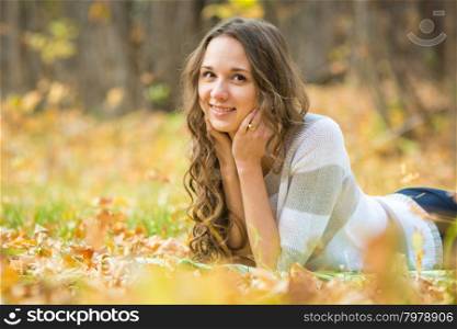 Twenty-five young beautiful girl walks by Europeans autumn forest. Young beautiful girl lies on the weave at a picnic in the autumn forest