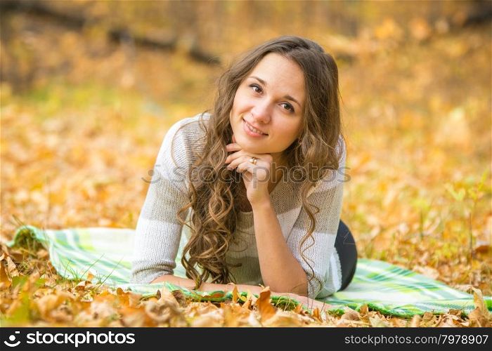 Twenty-five young beautiful girl walks by Europeans autumn forest. Young beautiful girl lying on a rug in the autumn forest
