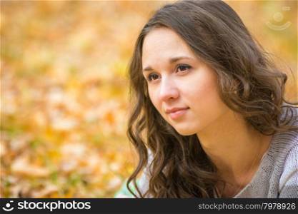 Twenty-five young beautiful girl walks by Europeans autumn forest. Close-up portrait of a beautiful young girl on the blurry background yellow foliage