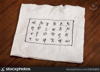 twenty four letters of Greek alphabet from alpha to omega (in lower case) handwritten on a white napkin