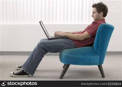 Twenty Something Caucasian Male Wearing Jeans And Using A Laptop