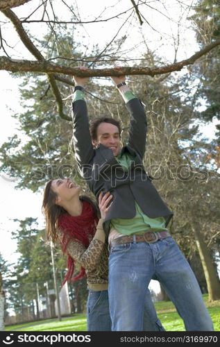 Twenty Something Female Helping Her Boyfriend Do A Pull Up In The Park